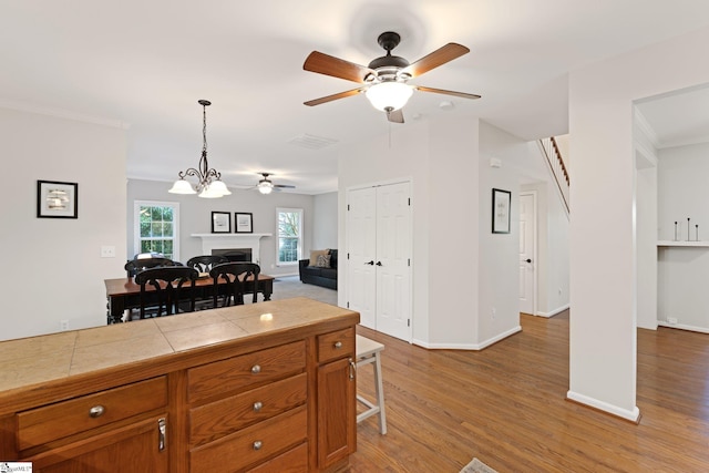 629 Germander Ct, Greer, SC 29651 - kitchen with ceiling fan, brown cabinets, a fireplace, wood finished floors, and crown molding