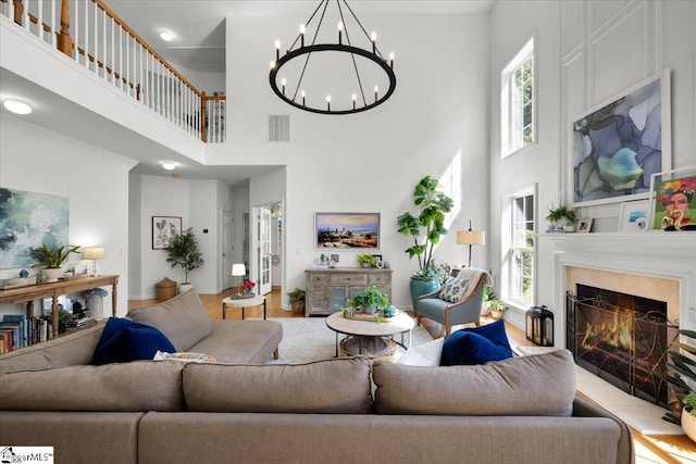 9 Springhead Way, Greer, SC 29650 - living room featuring a towering ceiling, a chandelier, a warm lit fireplace, and wood finished floors