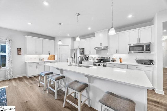 18 Yakama Way, Greenville, SC 29607 - kitchen featuring stainless steel appliances, light wood finished floors, decorative backsplash, an island with sink, and recessed lighting