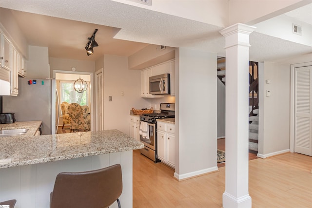 130 Inglewood Way, Greenville, SC 29615 - kitchen featuring appliances with stainless steel finishes, light wood finished floors, ornate columns, and white cabinetry