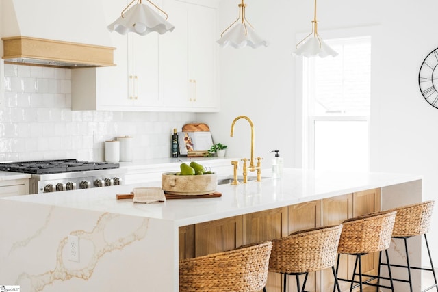 5 Martin Row, Greenville, SC 29601 - kitchen featuring custom exhaust hood, tasteful backsplash, light stone countertops, a kitchen breakfast bar, and white cabinetry
