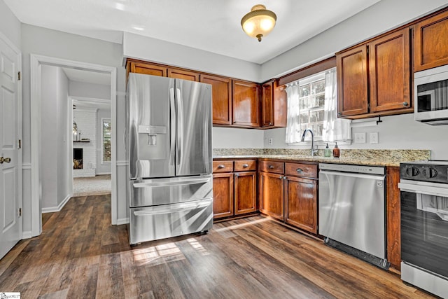203 Camellia Ln, Simpsonville, SC 29681 - kitchen featuring stainless steel appliances, dark wood-style floors, light stone counters, brown cabinets, and plenty of natural light