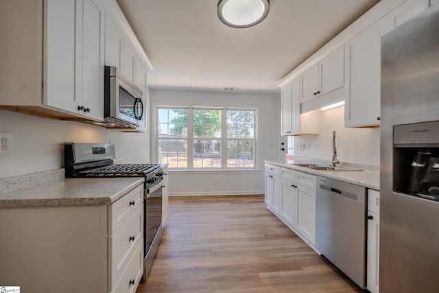 101 Clearbrook Ct, Greer, SC 29650 - kitchen featuring appliances with stainless steel finishes, light wood-type flooring, white cabinetry, and light stone counters
