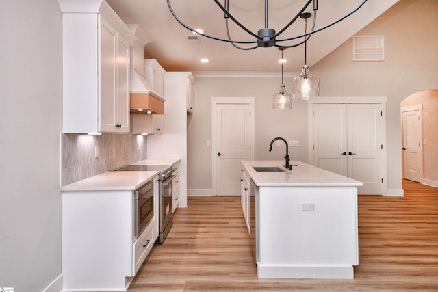 72 Seminole Dr, Simpsonville, SC 29680 - kitchen with white cabinets, arched walkways, decorative backsplash, a kitchen island with sink, and light countertops