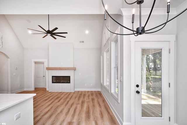 72 Seminole Dr, Simpsonville, SC 29680 - unfurnished living room with light wood-style flooring, a chandelier, arched walkways, high vaulted ceiling, and a glass covered fireplace