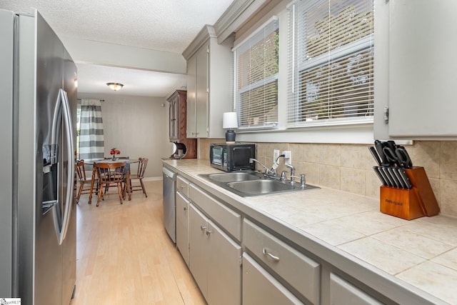2 Line St, Taylors, SC 29687 - kitchen featuring stainless steel appliances, tile countertops, light wood finished floors, decorative backsplash, and a textured ceiling