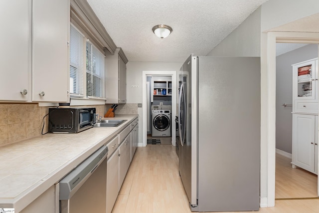 2 Line St, Taylors, SC 29687 - kitchen with tile countertops, stainless steel appliances, washer / dryer, light wood-type flooring, and a textured ceiling