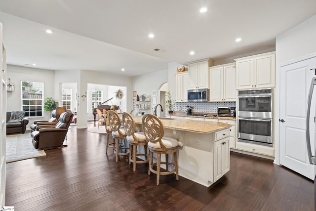 506 Bellot Winds Dr, Duncan, SC 29334 - kitchen featuring stainless steel appliances, arched walkways, light stone countertops, dark wood finished floors, and open floor plan