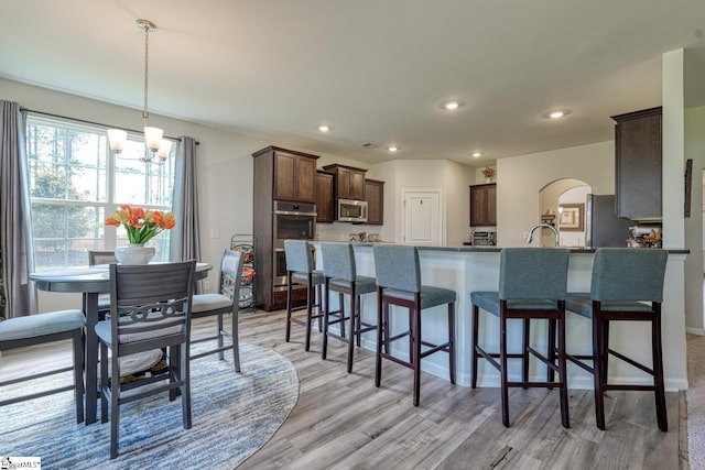 4002 Hometown Way, Boiling Springs, SC 29316 - kitchen featuring stainless steel appliances, dark brown cabinets, a kitchen breakfast bar, a chandelier, and light wood-style flooring