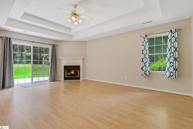 415 N Pond View Dr, Duncan, SC 29334 - unfurnished living room with a tray ceiling, light wood-style floors, a warm lit fireplace, and a ceiling fan