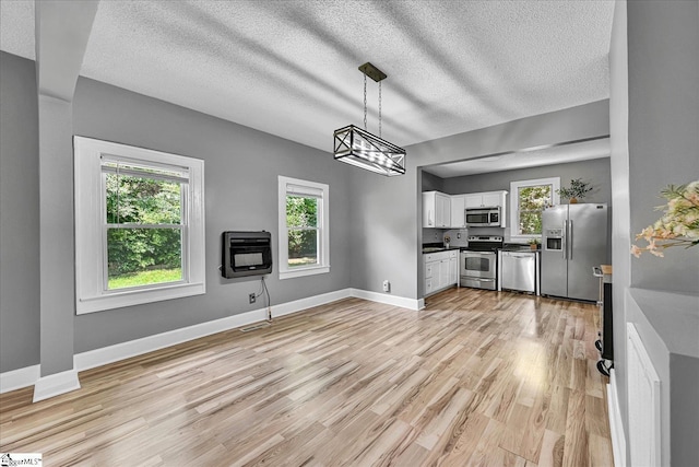 23 Stringer St, Belton, SC 29627 - kitchen with stainless steel appliances, heating unit, white cabinets, dark countertops, and light wood-type flooring
