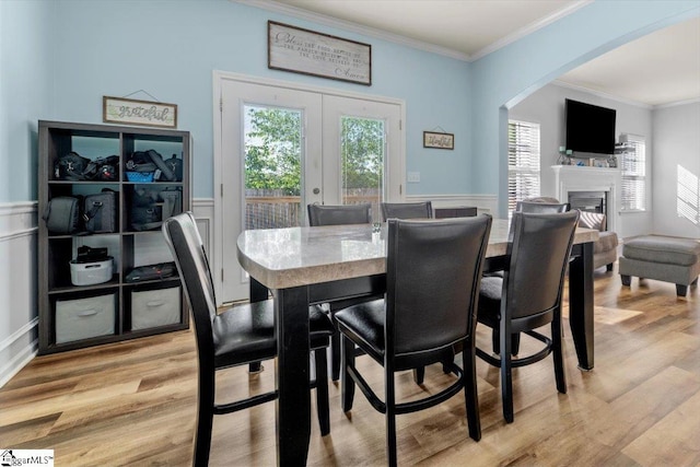 114 Eagles View Ct, Easley, SC 29642 - dining room with crown molding, light wood-style flooring, a glass covered fireplace, arched walkways, and a wainscoted wall