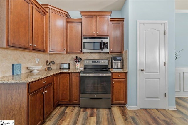 114 Eagles View Ct, Easley, SC 29642 - kitchen with appliances with stainless steel finishes, dark wood-style flooring, light stone countertops, decorative backsplash, and brown cabinetry