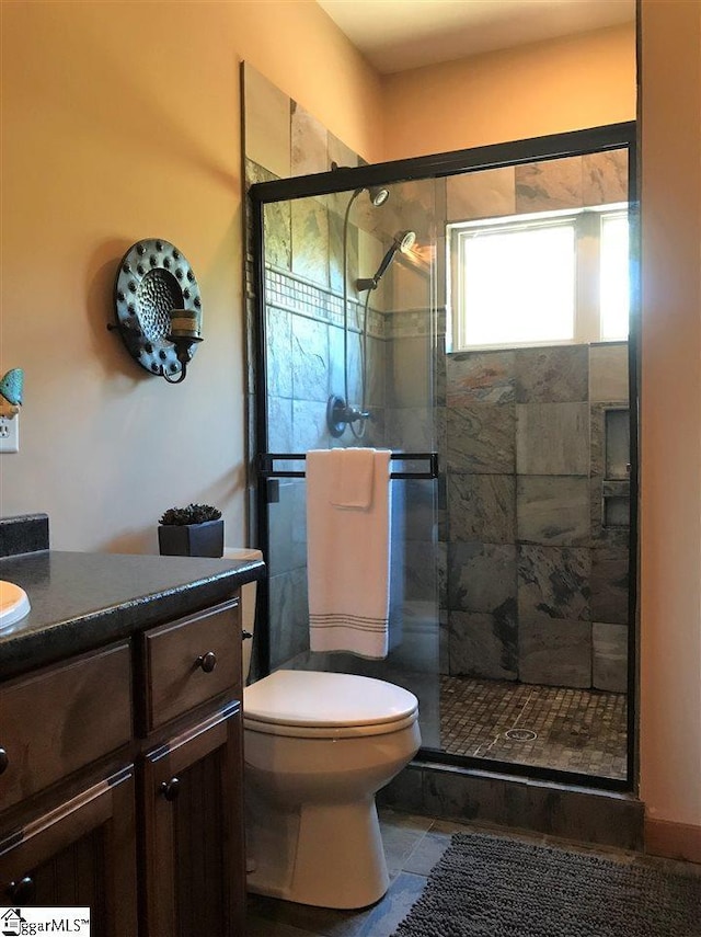 bathroom with an enclosed shower, toilet, vanity, and tile flooring