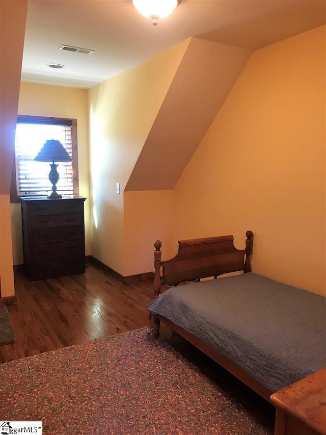 bedroom with lofted ceiling and dark hardwood / wood-style floors