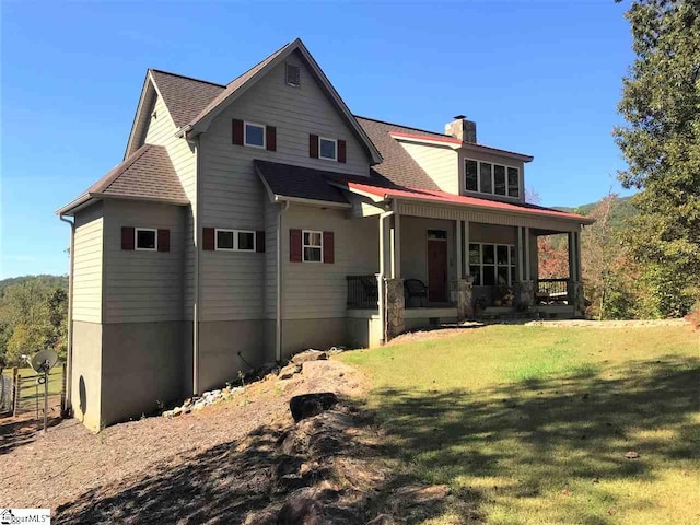 rear view of property featuring a porch and a lawn