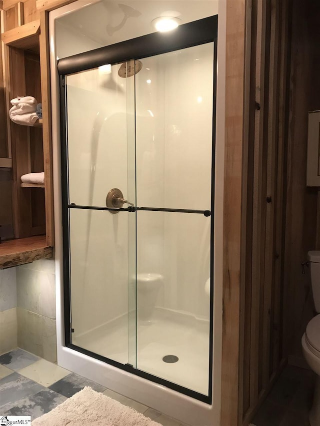 bathroom with toilet and a shower with door