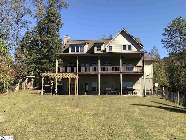 rear view of property with a balcony and a lawn