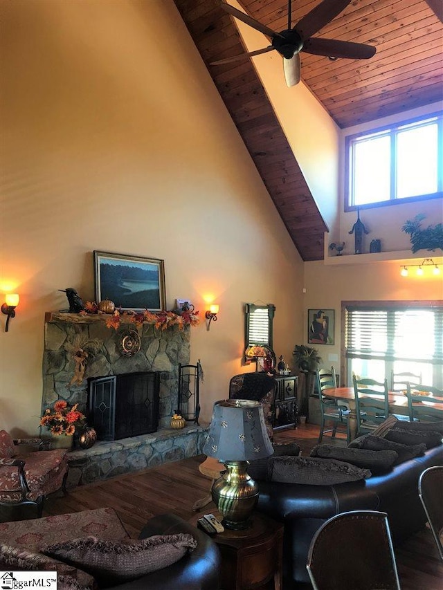 living room featuring ceiling fan, wooden ceiling, wood-type flooring, high vaulted ceiling, and a stone fireplace