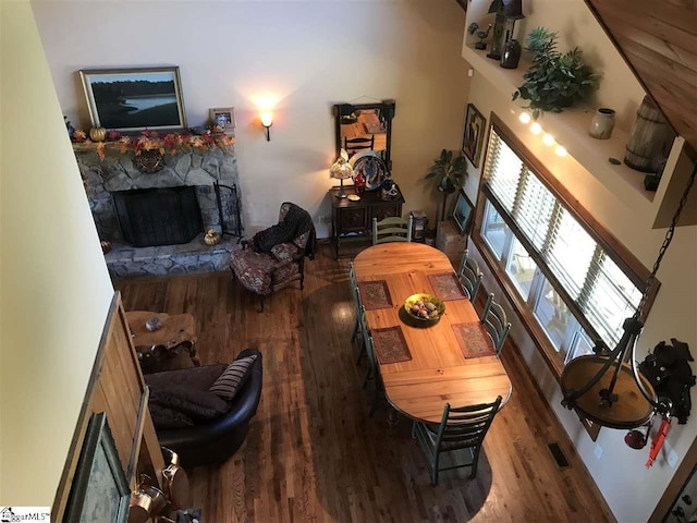 living room featuring a high ceiling, a fireplace, and hardwood / wood-style flooring