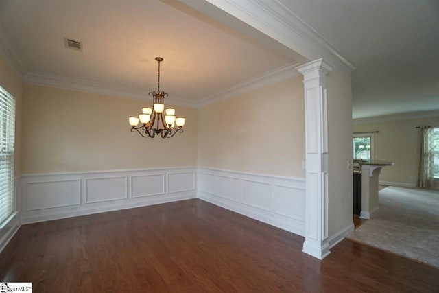 empty room with ornamental molding, dark hardwood / wood-style floors, a chandelier, and decorative columns