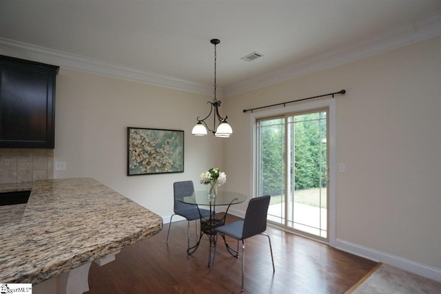 dining space featuring a notable chandelier, dark wood-type flooring, and ornamental molding