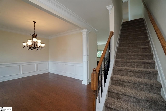 staircase featuring a notable chandelier, crown molding, dark hardwood / wood-style floors, and ornate columns