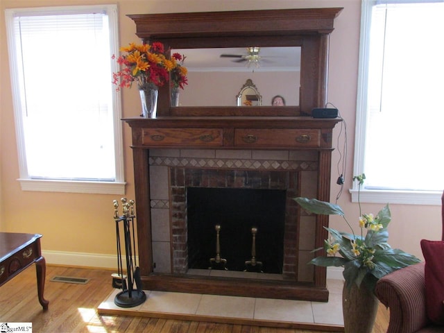 details with ceiling fan, a tile fireplace, light hardwood / wood-style flooring, and crown molding