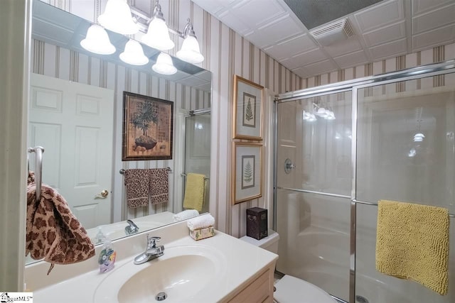 bathroom with toilet, a shower with shower door, and vanity with extensive cabinet space