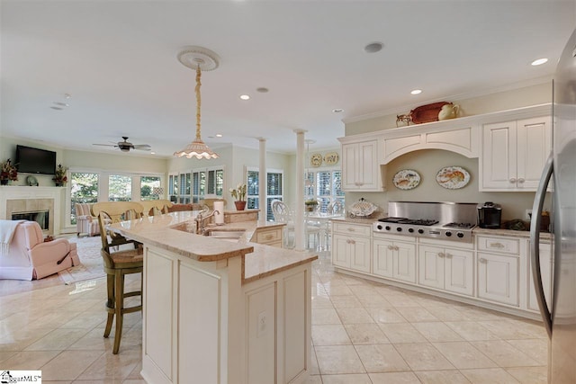 kitchen featuring a fireplace, ceiling fan, a center island with sink, hanging light fixtures, and sink