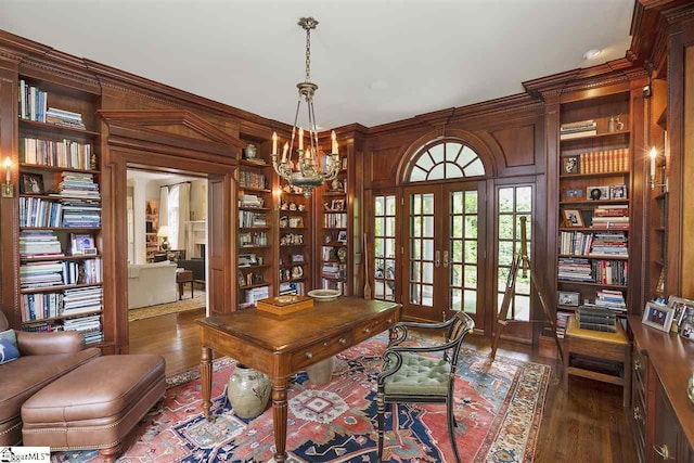 office area featuring dark hardwood / wood-style floors, french doors, wooden walls, built in features, and an inviting chandelier