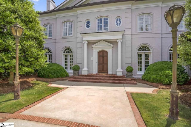 view of exterior entry featuring french doors and a lawn