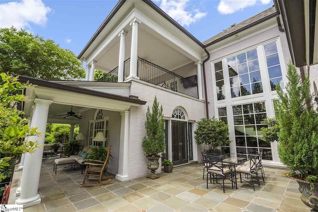 rear view of property with ceiling fan, a balcony, and a patio area