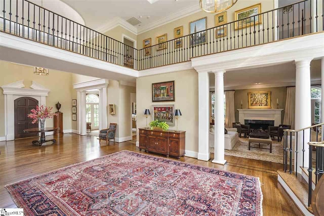 entryway featuring crown molding, dark hardwood / wood-style flooring, decorative columns, and a high ceiling