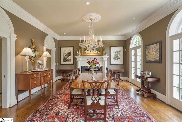 dining space with ornamental molding, wood-type flooring, and an inviting chandelier