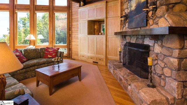 living room featuring light hardwood / wood-style flooring, a fireplace, and wood walls