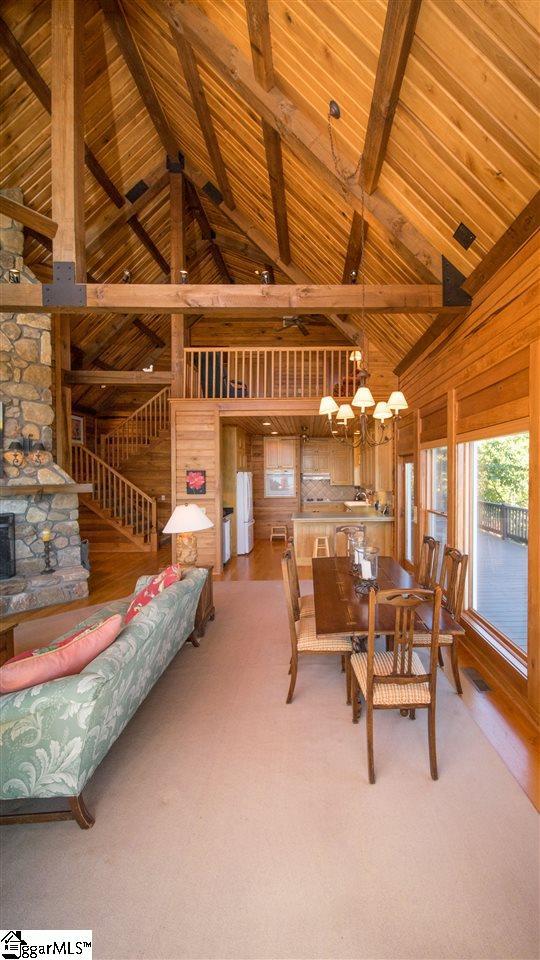 dining room with a notable chandelier, beam ceiling, a fireplace, and wooden ceiling