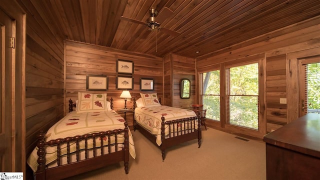 carpeted bedroom with ceiling fan, wooden ceiling, and wood walls