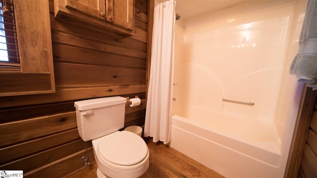 bathroom featuring wood-type flooring, shower / bath combo with shower curtain, and toilet