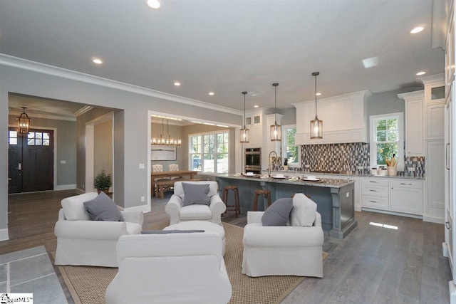 living room featuring dark wood-type flooring, ornamental molding, and a chandelier