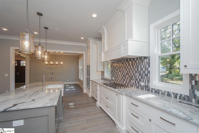 kitchen with light stone countertops, decorative light fixtures, backsplash, and white cabinetry