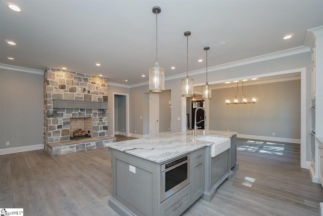 kitchen with wood-type flooring, sink, and an island with sink