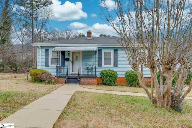 bungalow-style home with covered porch and a front lawn