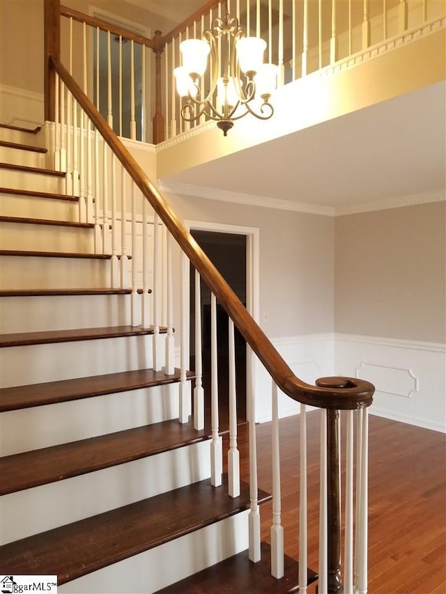 stairs featuring crown molding, dark hardwood / wood-style floors, and an inviting chandelier