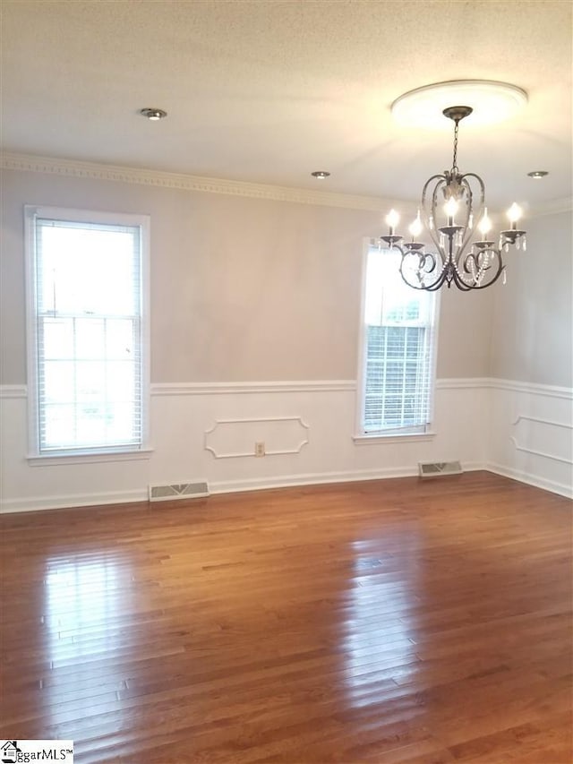 spare room featuring plenty of natural light, a chandelier, and hardwood / wood-style flooring