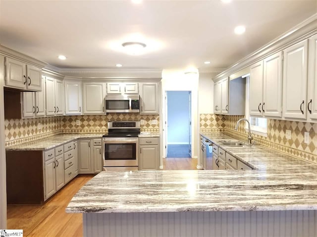 kitchen with kitchen peninsula, sink, backsplash, light hardwood / wood-style floors, and stainless steel appliances