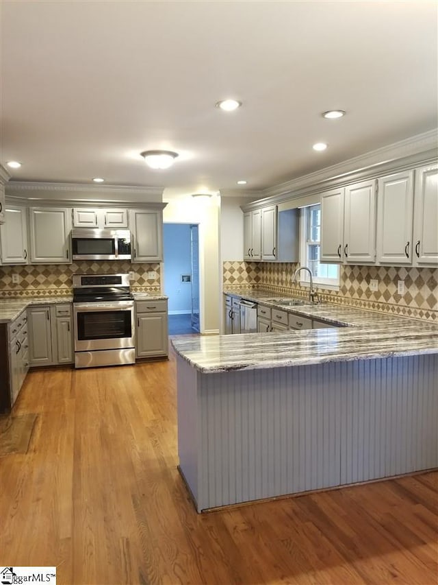 kitchen featuring kitchen peninsula, sink, gray cabinetry, appliances with stainless steel finishes, and light hardwood / wood-style flooring