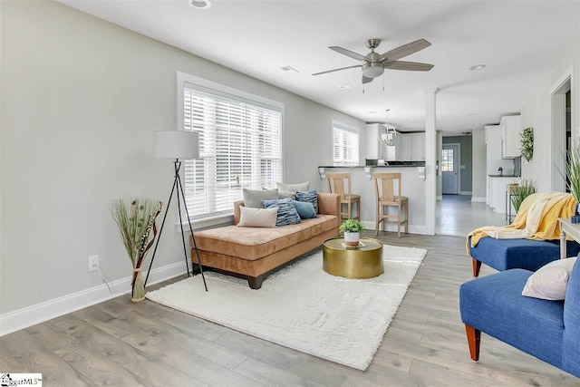 living room with light hardwood / wood-style floors and ceiling fan with notable chandelier