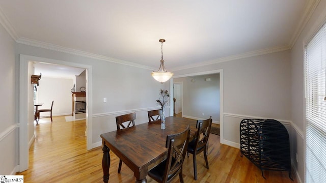 dining space with light wood-type flooring and ornamental molding