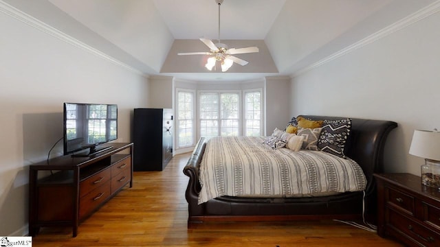 bedroom featuring ceiling fan, crown molding, light hardwood / wood-style flooring, and vaulted ceiling